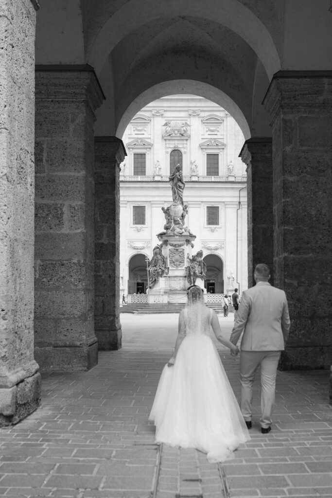 Schwarz weiß Aufnahme von einem Brautpaar, dass durch ein Tor geht.