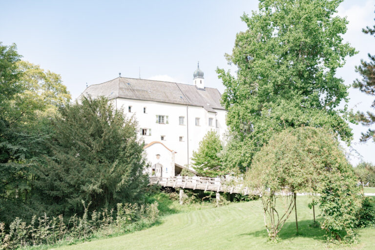 Außenansicht einer Schlosslocation in Amerang mit einer Brücke und Bäumen im Vordergrund bei einer Hochzeit im Sommer