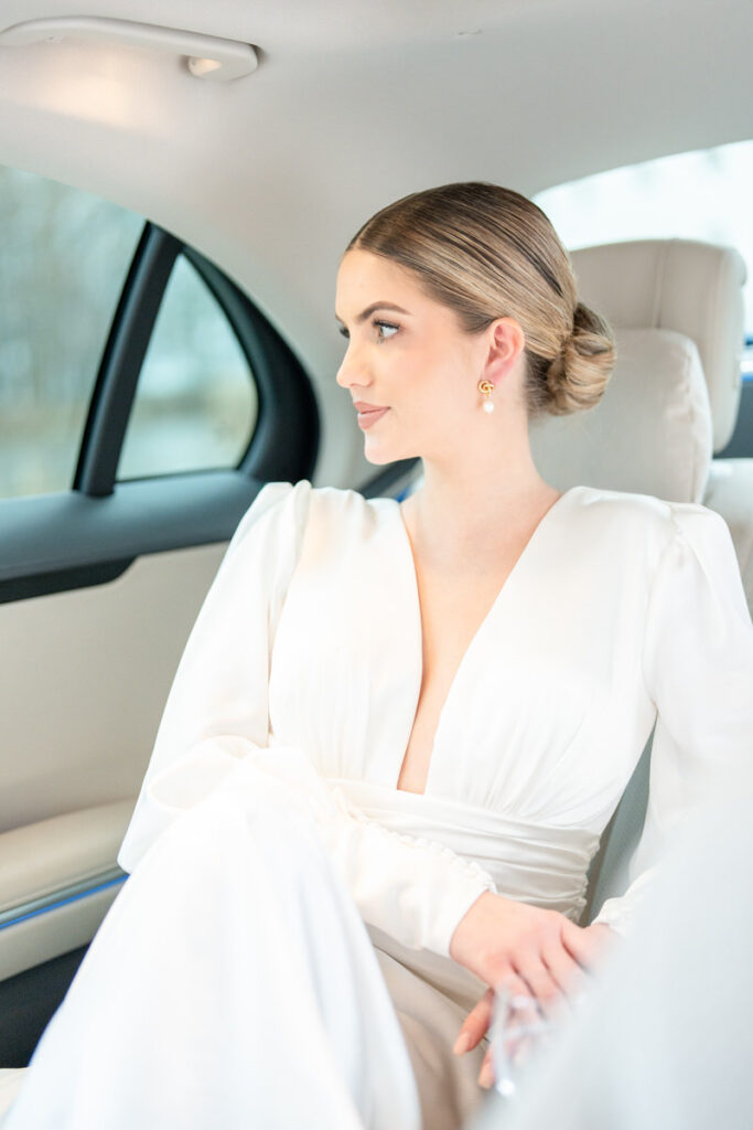 Braut sitzt im Hochzeitsauto und blickt aus dem Fenster bevor die Hochzeit beginnt