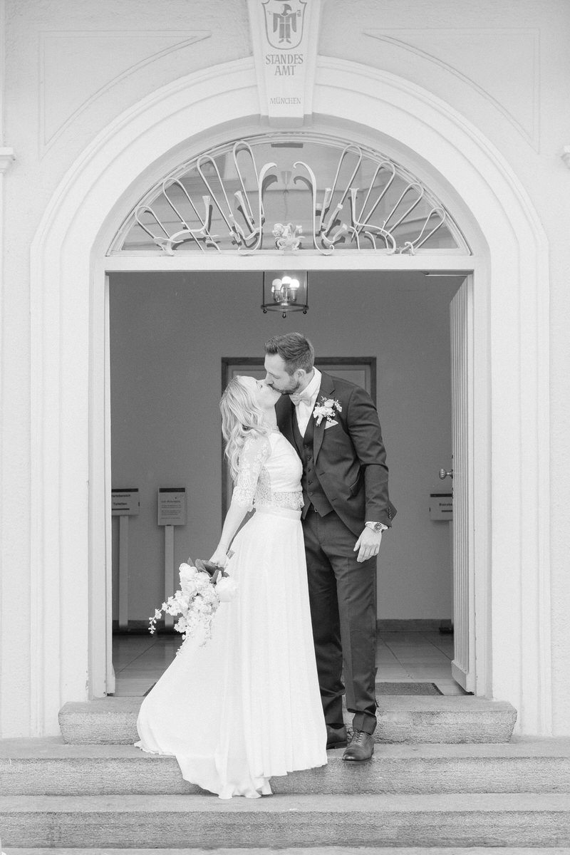 Inniger Kuss zwischen Brautpaar vor dem Eingang des Standesamtes München nach der Hochzeitszeremonie