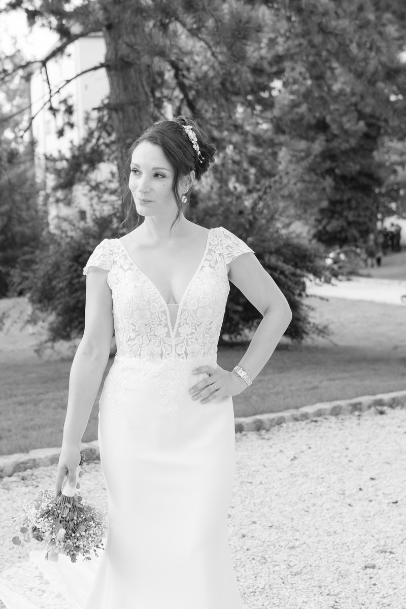 Braut mit einem spitzenbesetzten Brautkleid und einem Brautstrauß posiert für den Hochzeitsfotografen Rosenheim