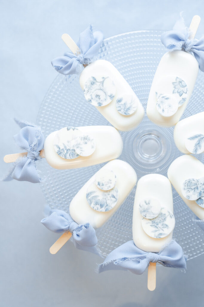 Kleine Hochzeitskuchen mit blauer Dekoration und blauen Satinbändern im Kreis auf einem Kuchenteller angerichtet