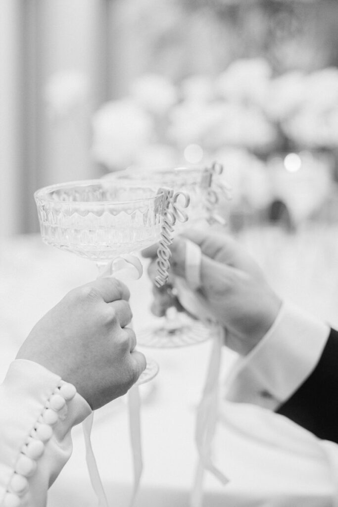 Detailaufnahme in schwarz weiß von zwei Champagnergläsern und weißen Schleifen - aufgenommen von Hochzeitsfotograf Rosenheim