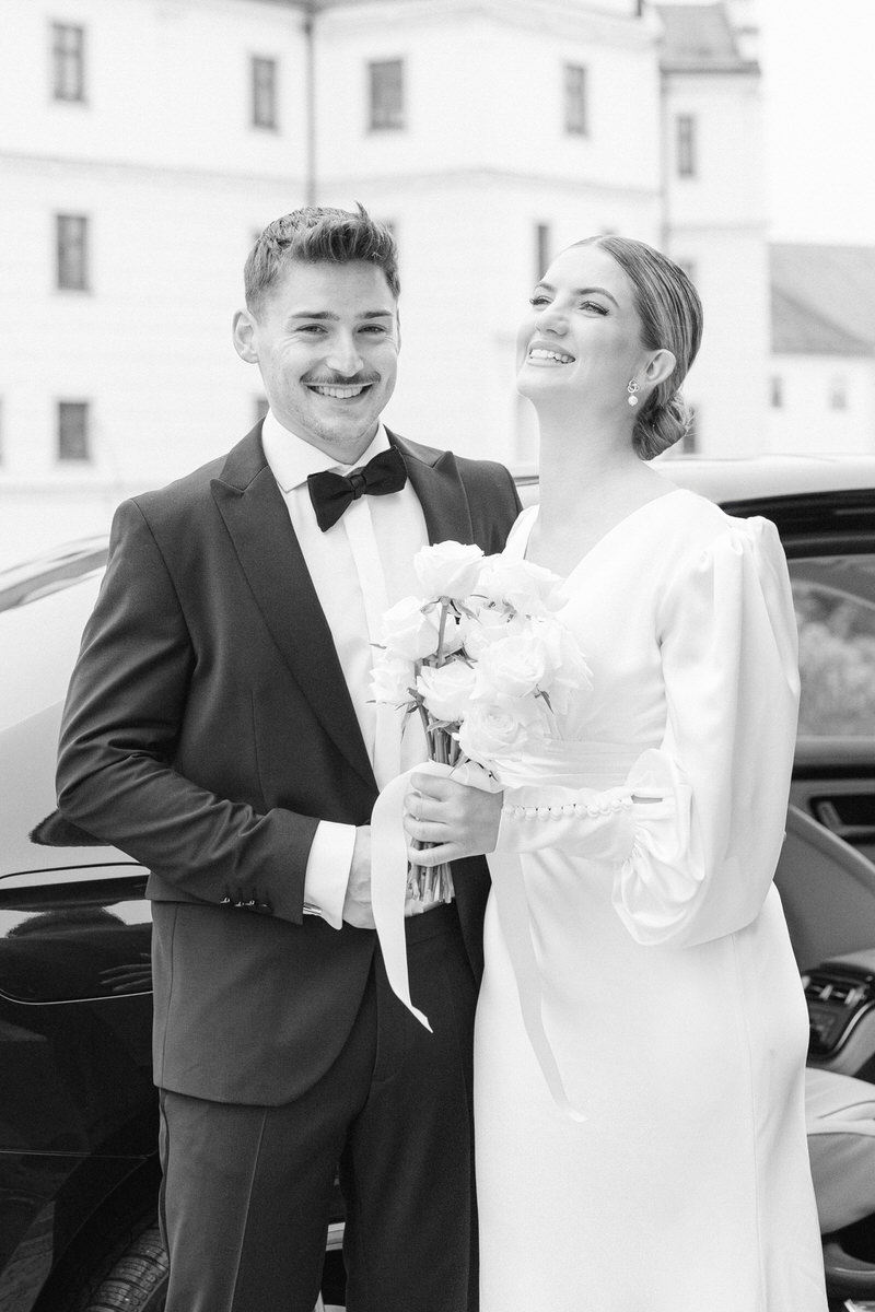 Ein lachendes Ehepaar bei ihrer Hochzeit im Schloss - von Hochzeitsfotograf Rosenheim in schwarz weiß aufgenommen
