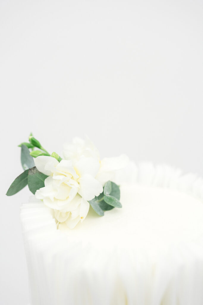 Nahaufnahme von einer Hochzeitstorte mit weißer Tortendekoration aus frischen Blumen