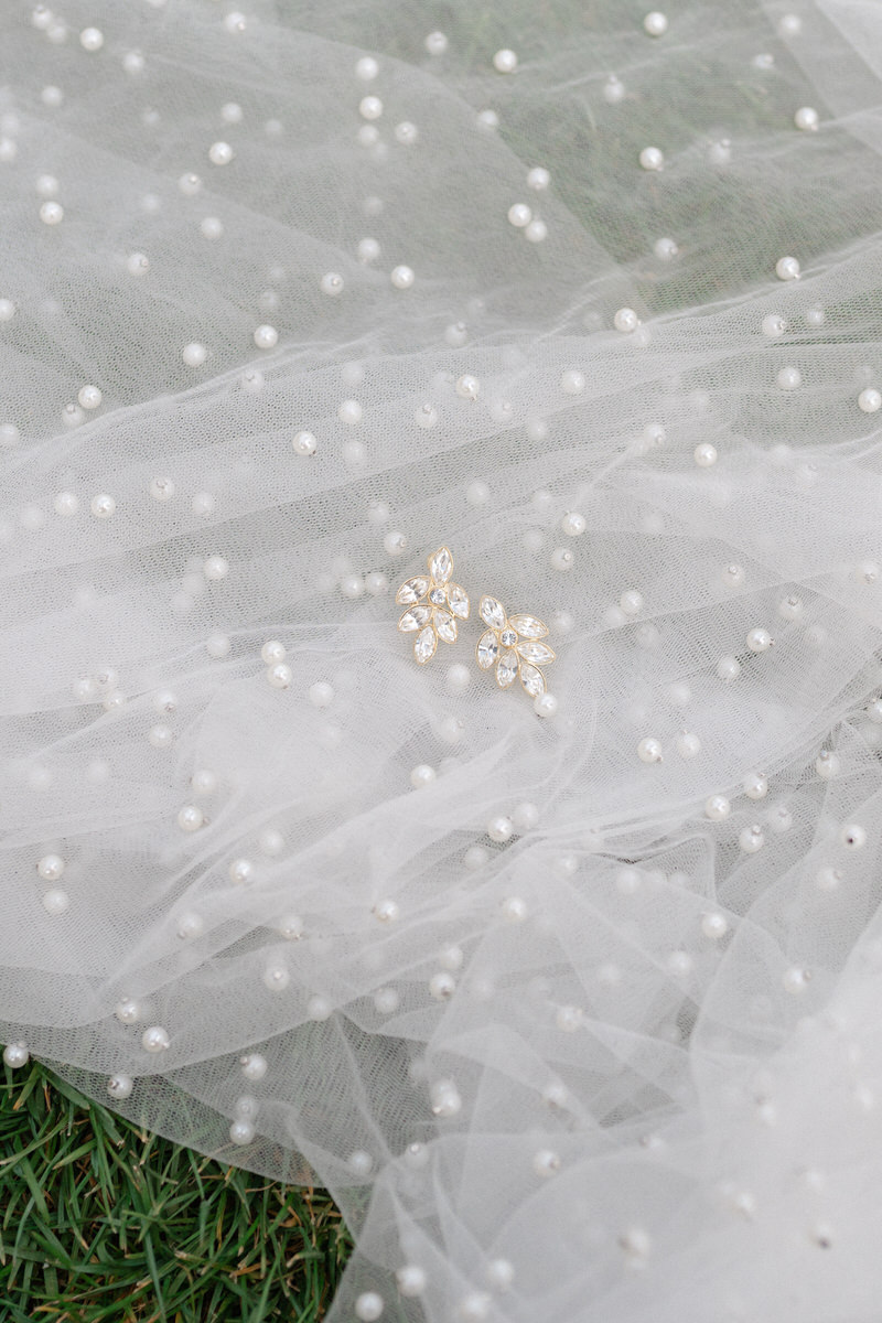 Nahaufnahme von Hochzeitsschmuck, der auf einem Schleier mit Perlen liegt