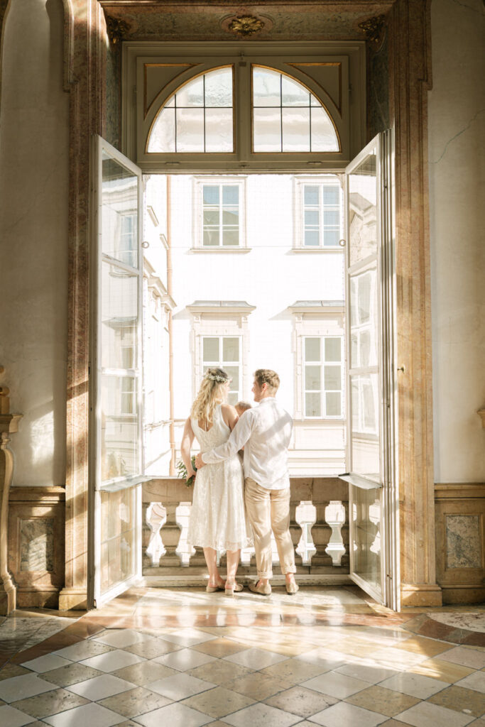 Elegantes Brautpaar sieht aus dem Fenster nach ihrer standesamtlichen Trauung