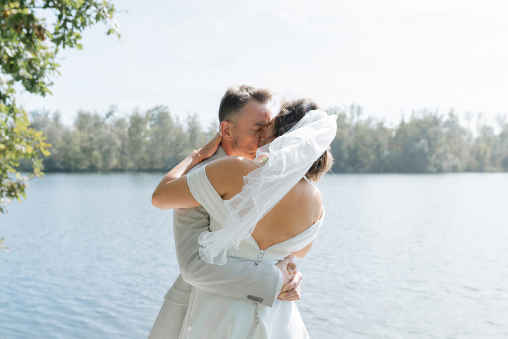 Brautpaar küsst sich bei ihrem first look vor der Hochzeit am Happiger See in Rosenheim