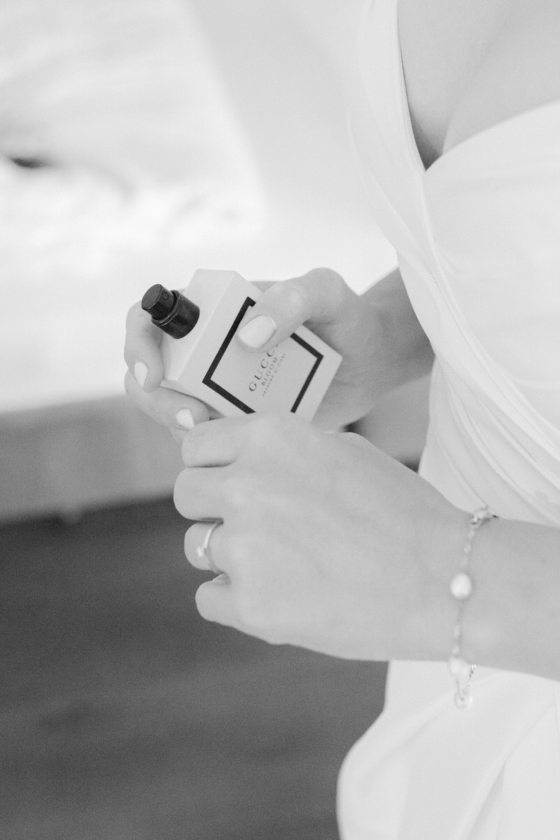 Braut hält ein Parfüm bei ihrem getting ready in Händen in schwarz weiß fotografiert