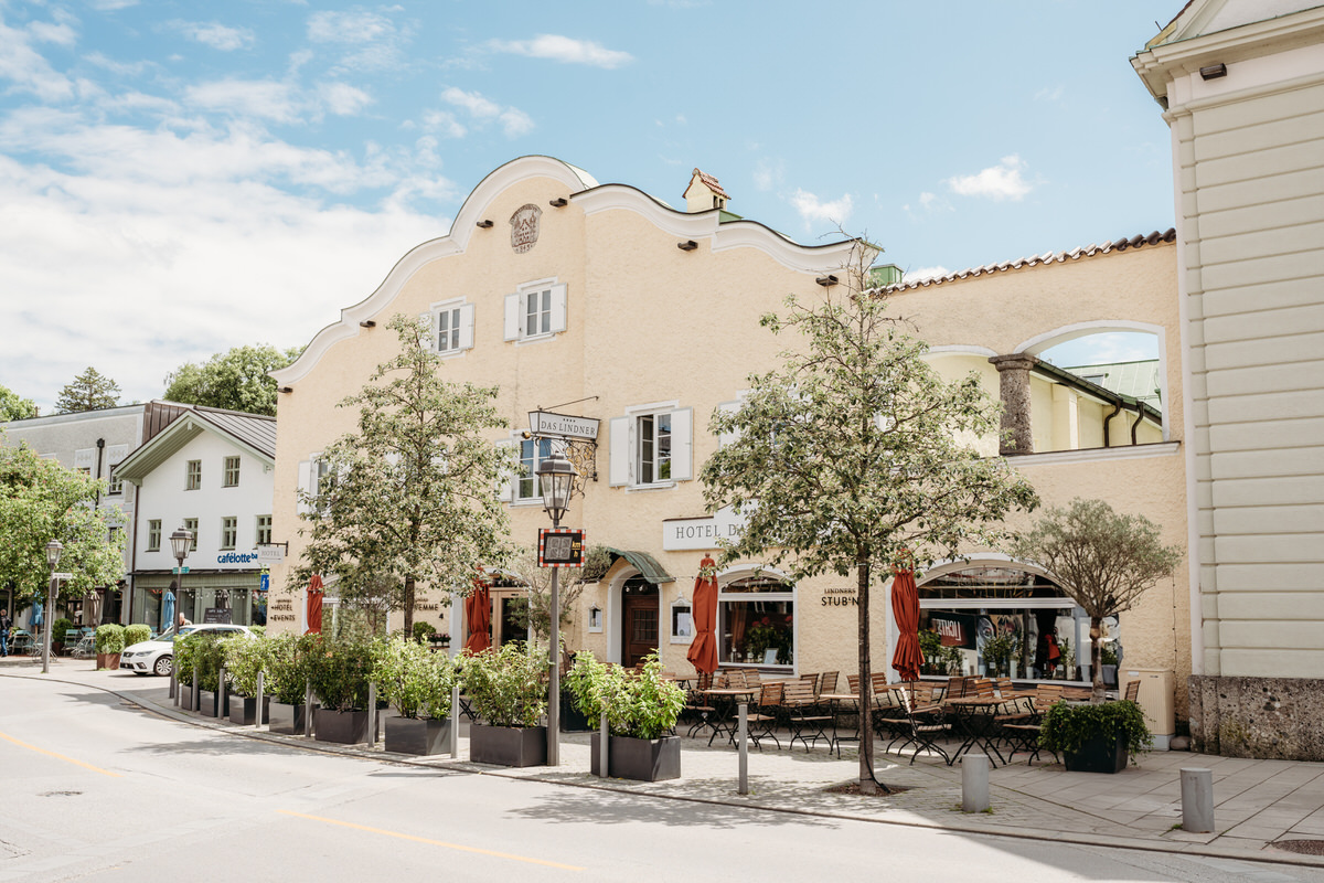 Außenaufnahme von der Hochzeitslocation Hotel Linder in Bad Aibling mit blauem Himmel und Olivenstämmen im Vordergrund