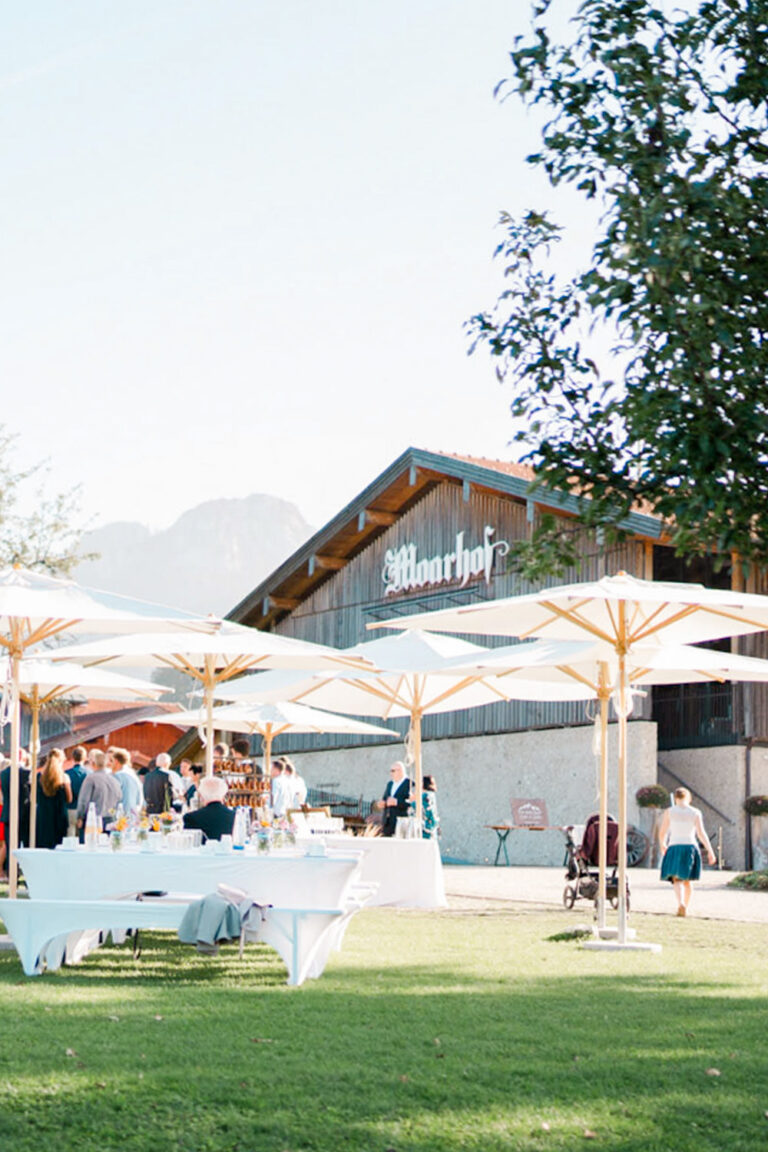 Außenansicht von Hochzeitslocation Moarhof nahe Rosenheim mit Hochzeitsgesellschaft und Stehempfang bei sonnigem Wetter