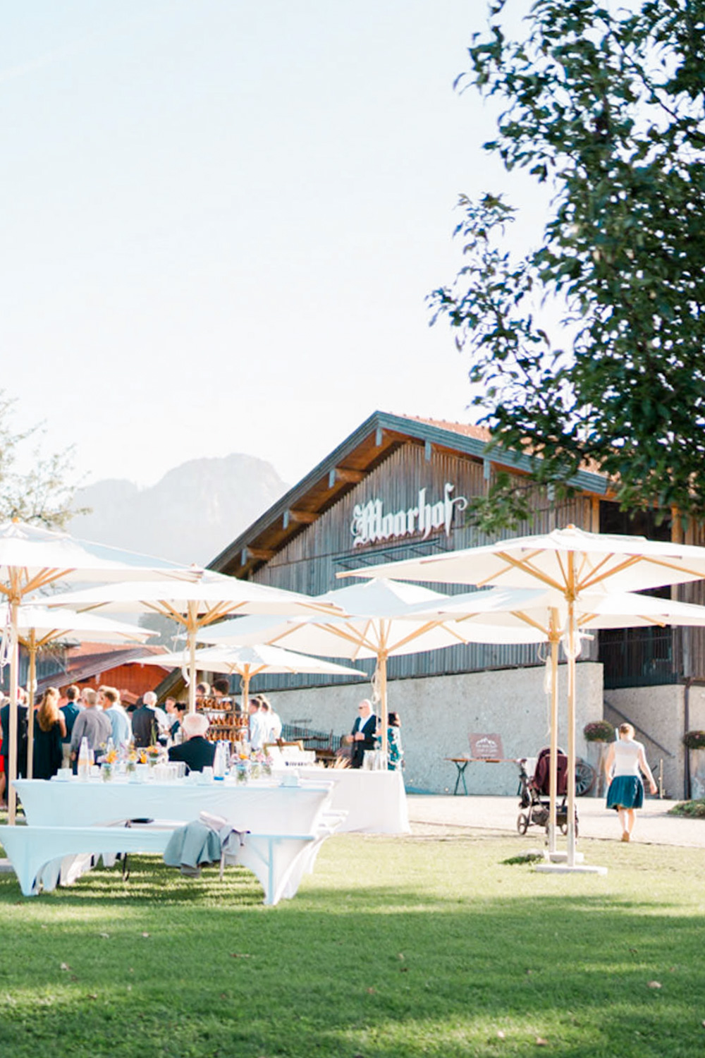 Außenansicht von Hochzeitslocation Moarhof nahe Rosenheim mit Hochzeitsgesellschaft und Stehempfang bei sonnigem Wetter