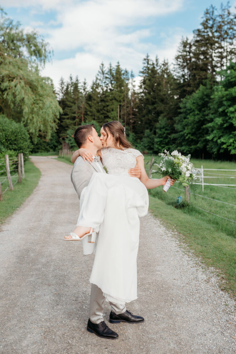 Bräutigam trägt Braut auf den Händen während einem romantischen Hochzeitsshooting in der Waldgaststätte Filzenklas bei Tuntenhausen