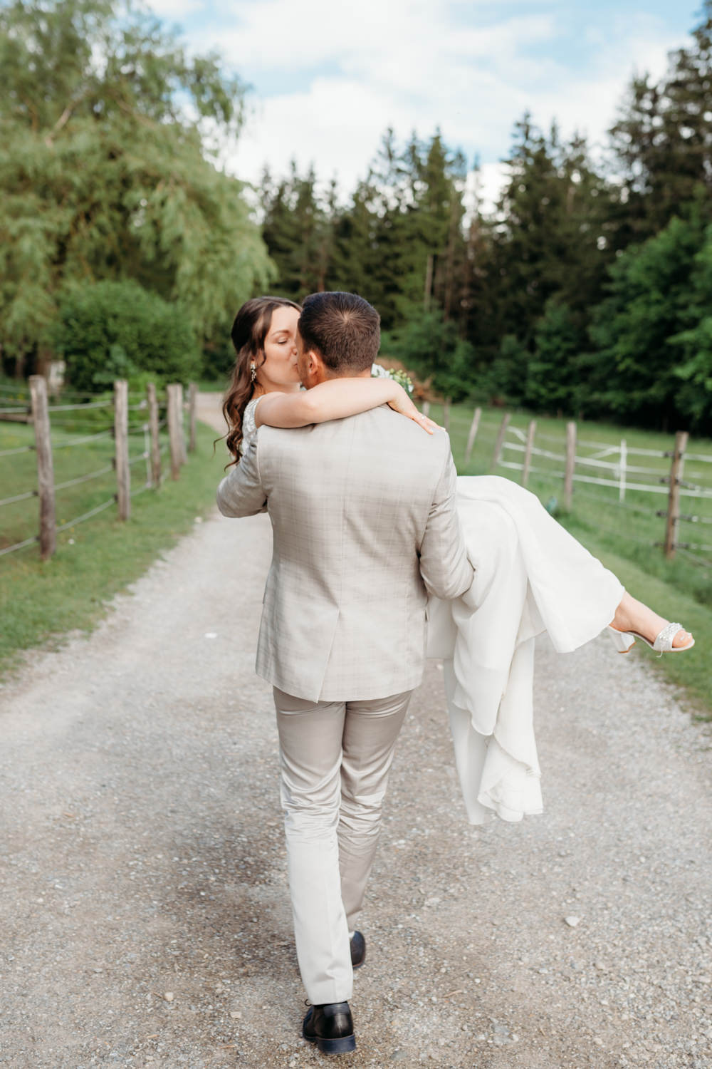 Bräutigam trägt Braut auf den Händen während dem Hochzeitsshooting in Tuntenhausen mit Hochzeitsfotograf Rosenheim.